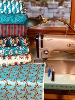 A stack of colorful fabric beside an antique Pfaff industrial sewing machine 