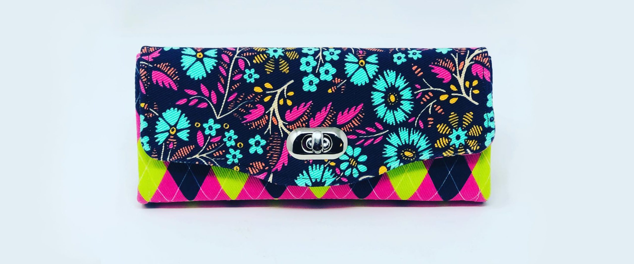 a brightly colored clutch wallet with a clasp and floral fabric