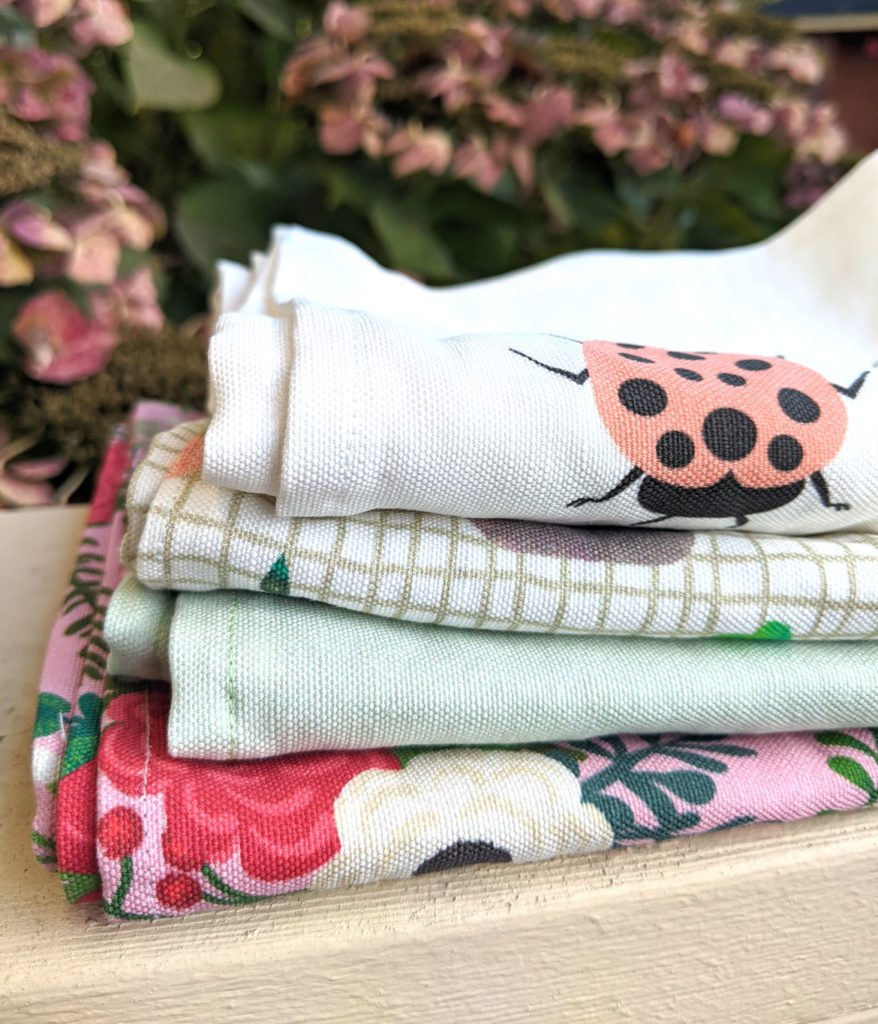 a stack of handmade linen tea towels with a lady bug, check and floral design

