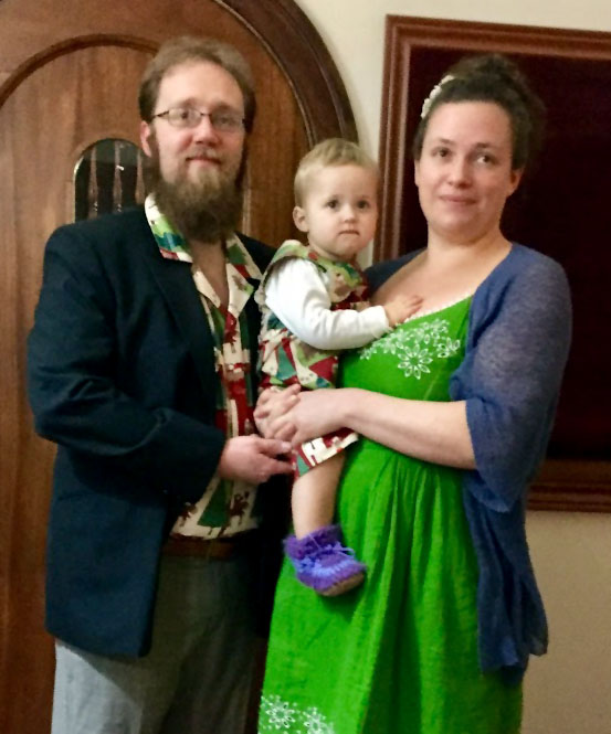 a mother, father and daughter dressed up for a Christmas party, the father and daughter are wearing matching Christmas outfits.