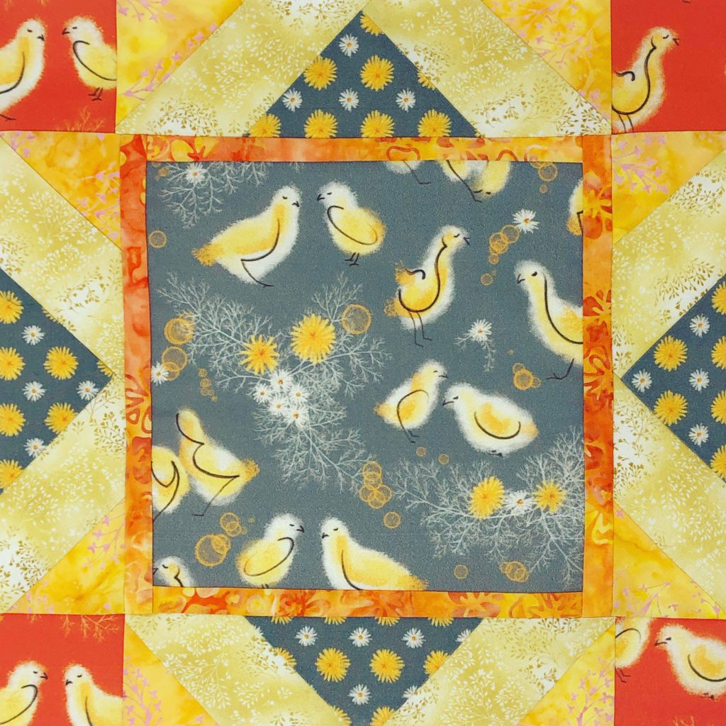 a quilt block with yellow and grey fabric and a design that has baby chickens
